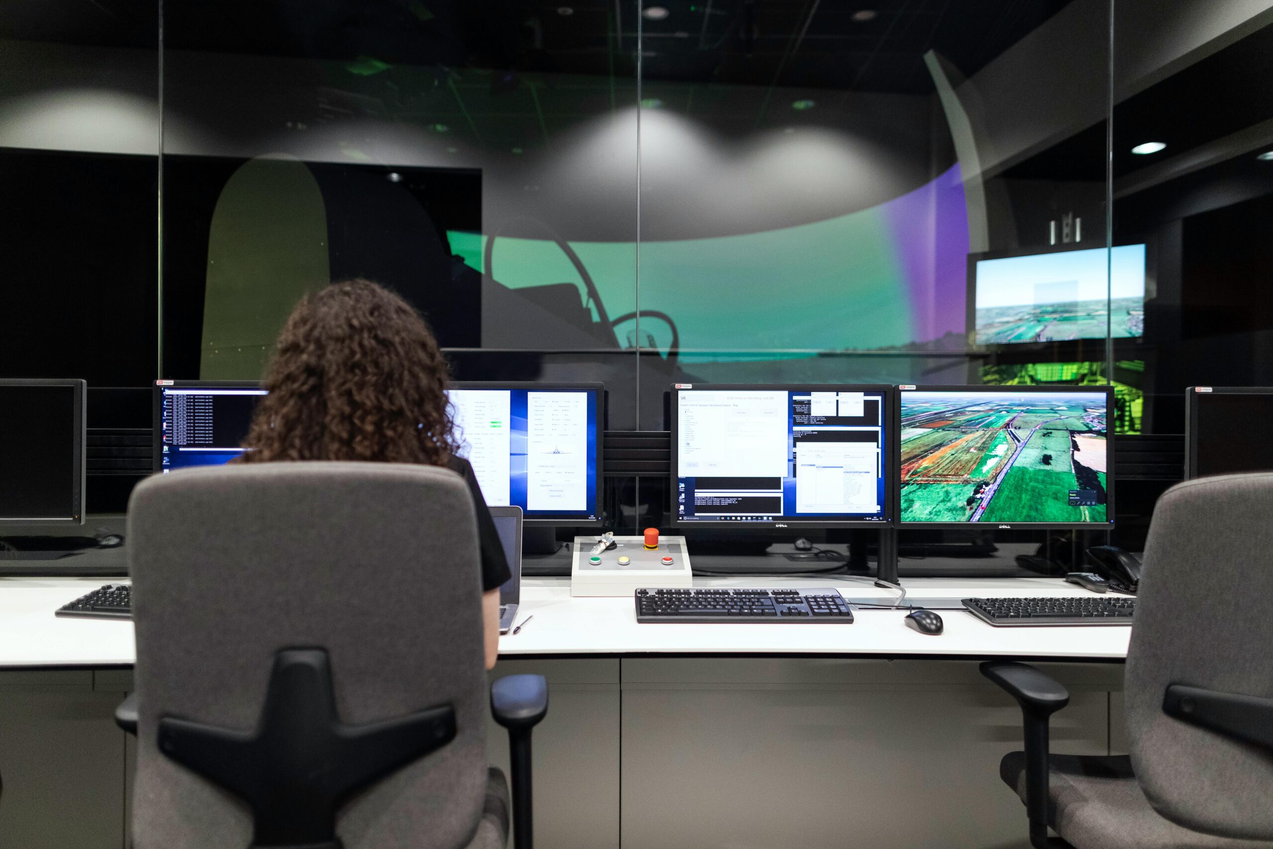 Female engineer managing multiple screens during a technology simulation in a control room.