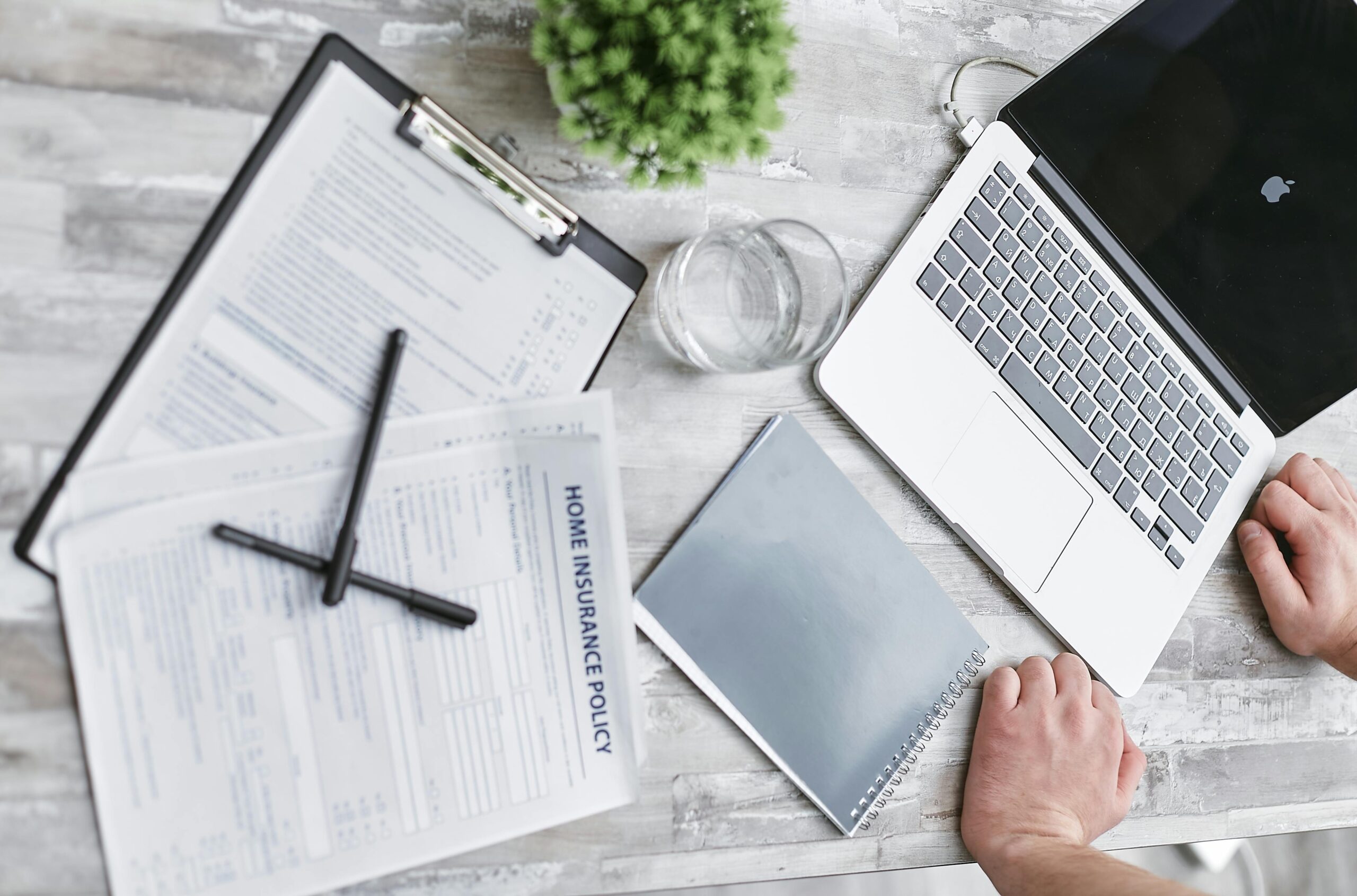 Top view of home insurance forms, laptop, and documents on a desk, conveying a professional office setting.