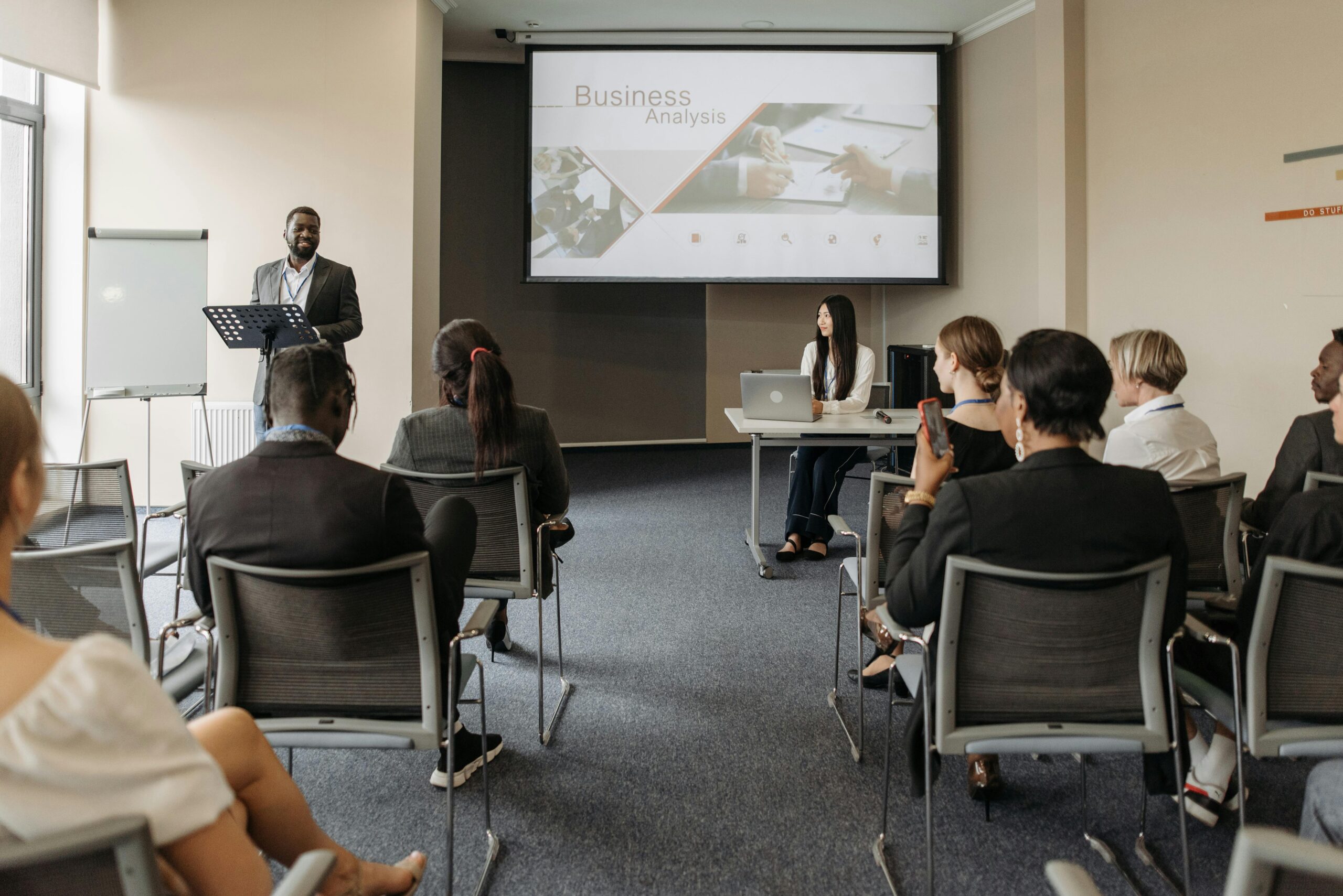 A diverse group of adults attending a presentation in a conference room setting.